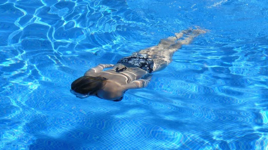 Woman enjoying time in swimming pool, showcasing swimwear fit and fabric performance in water