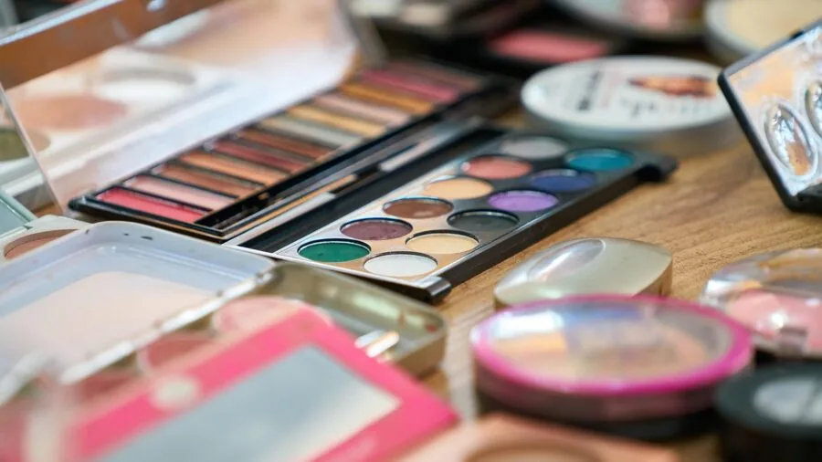 Woman examining different beauty products on table, comparing options and reading labels