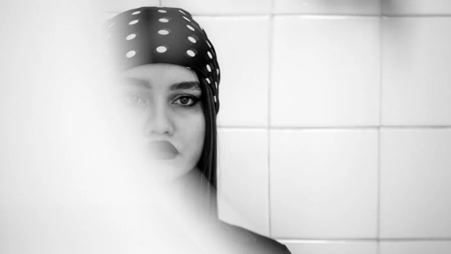 Woman examining her face in bathroom mirror during skincare routine
