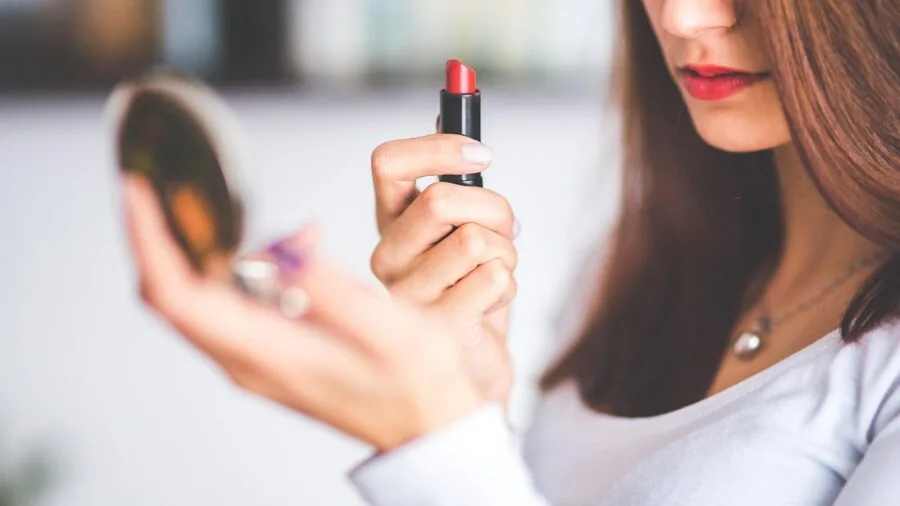 Woman examining her makeup in mirror during daytime to check foundation wear and longevity