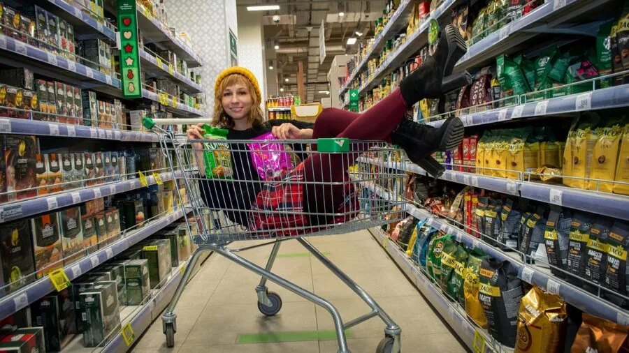 Woman examining personal care products on store shelf while shopping for affordable hygiene items
