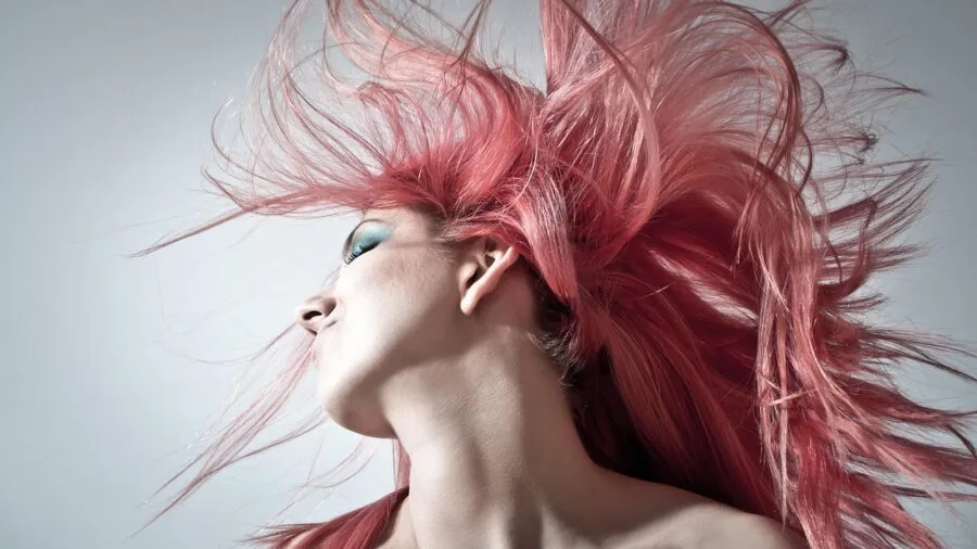 Woman examining the texture and condition of her color-treated hair in natural light