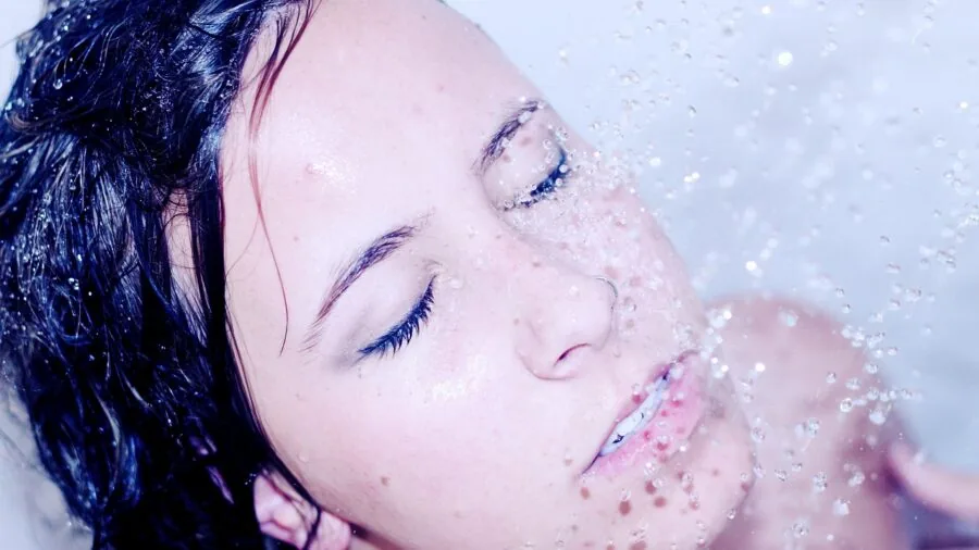 Woman exfoliating her skin during shower as part of skincare preparation routine