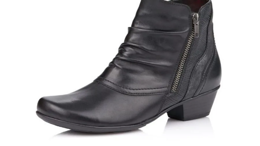 Woman fastening ankle boot closure while getting dressed in morning routine