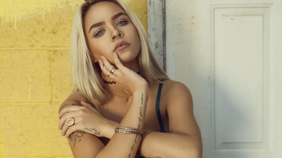 Woman gently touching her ear, showing a fresh piercing with a delicate stud earring