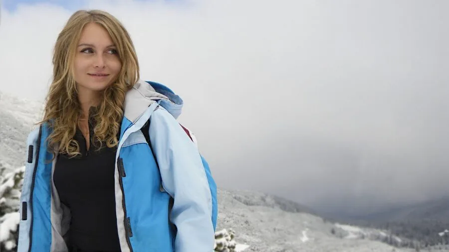 Woman hiking on mountain trail wearing outdoor gear and shorts