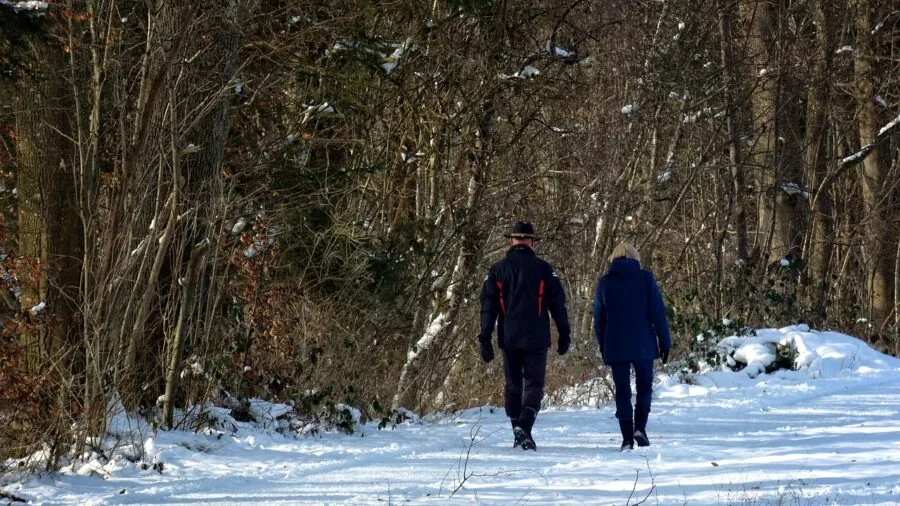 Woman hiking through snow-covered forest path in winter boots, demonstrating outdoor warmth and insulation