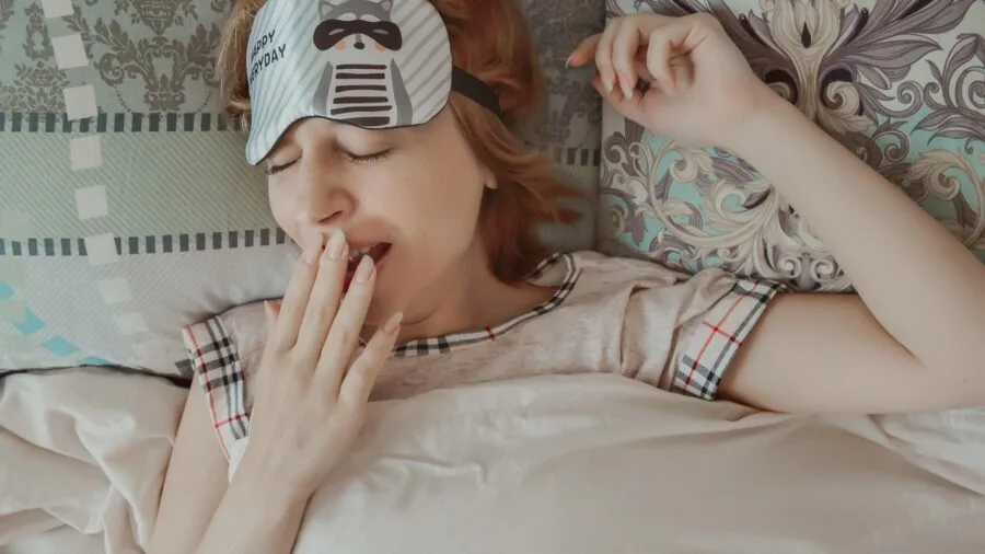 Woman holding hair styling tool above head, showing arm fatigue and effort during beauty routine