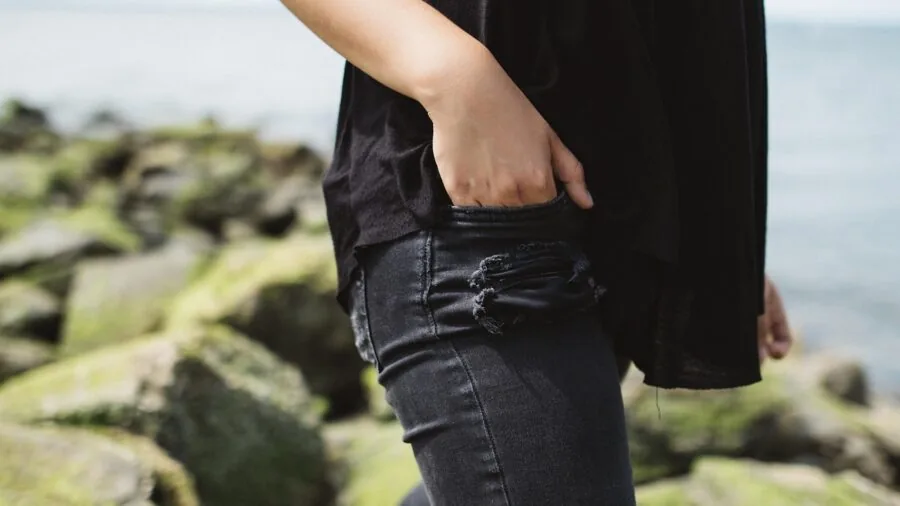 Woman in athletic leggings checking side pocket while exercising outdoors