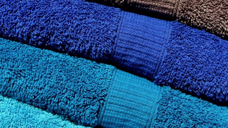 Woman in bathroom wrapping herself in soft absorbent terry cloth bathrobe after shower