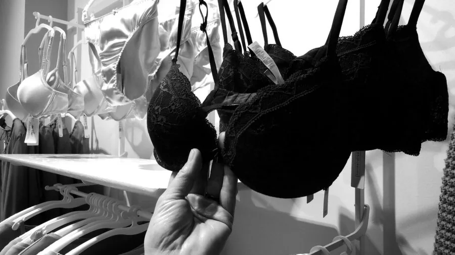 Woman in casual clothing adjusting and checking bra fit in front of mirror for proper band support