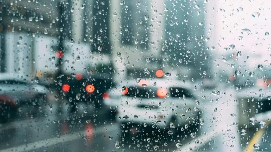 Woman in classic trench coat walking through rain, demonstrating water-resistant fabric durability