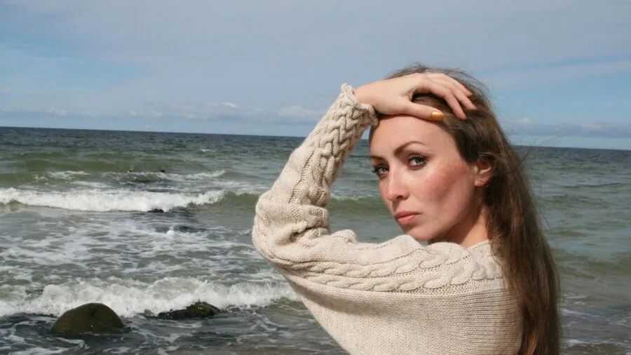 Woman in natural fiber sweater enjoying outdoor autumn setting, demonstrating comfort and quality fabric
