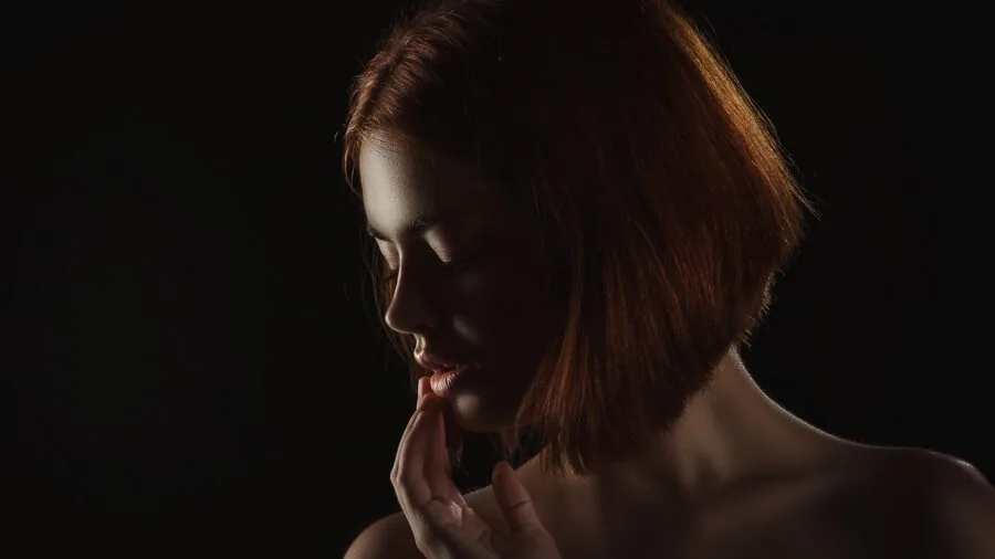 Woman in natural light applying lip balm as part of her daily skincare routine