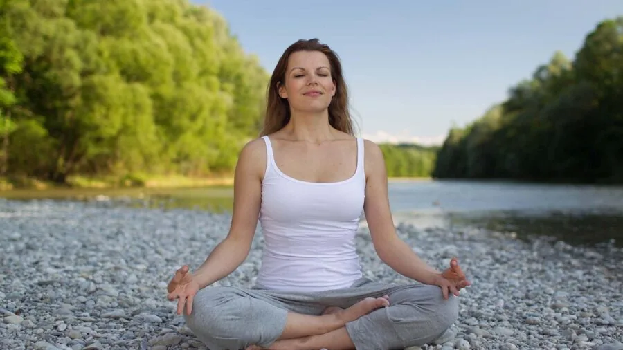 Woman in peaceful yoga pose on mat during restorative practice session indoors