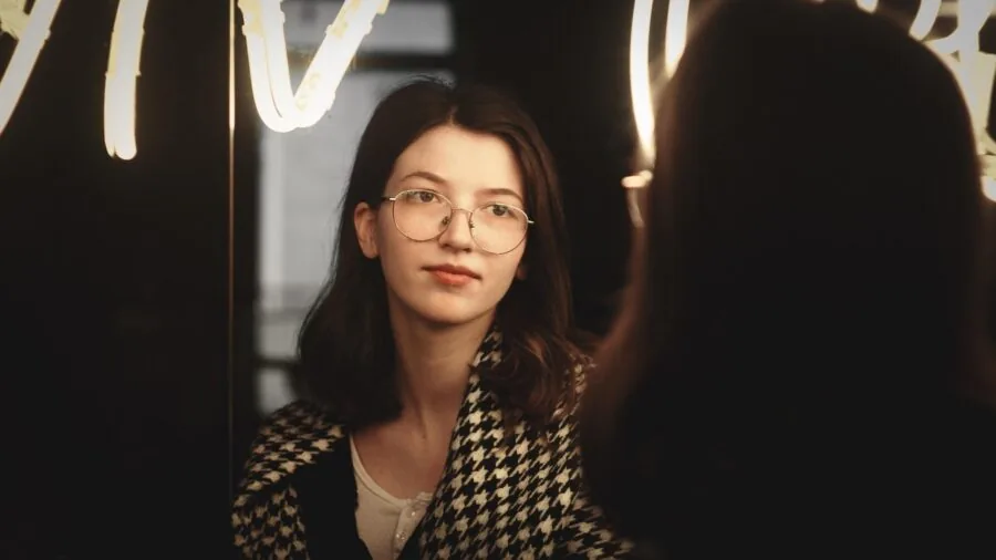 Woman inspecting high-quality mirror glass for clarity and reflection accuracy in home interior