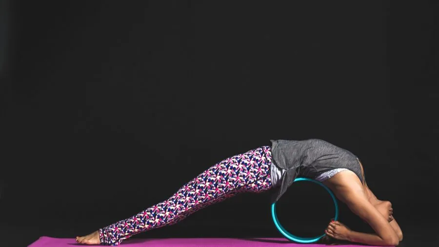 Woman organizing yoga equipment and mat into gym bag for portable fitness storage