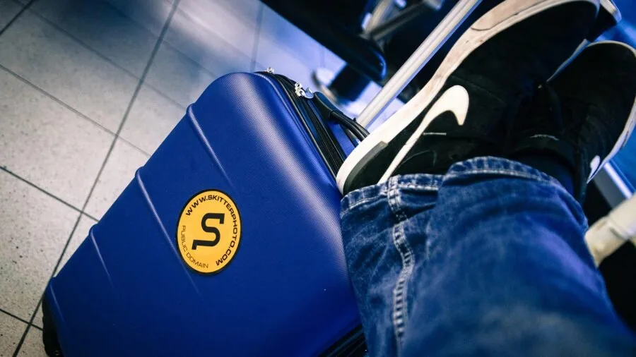 Woman packing suitcase with travel essentials and checking international power adapter compatibility