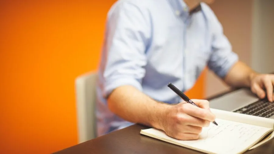 Woman reviewing finances and making notes in a notebook while planning household budget and expenses
