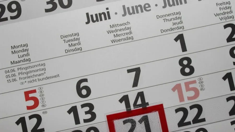 Woman reviewing monthly budget and expenses on calendar at home desk