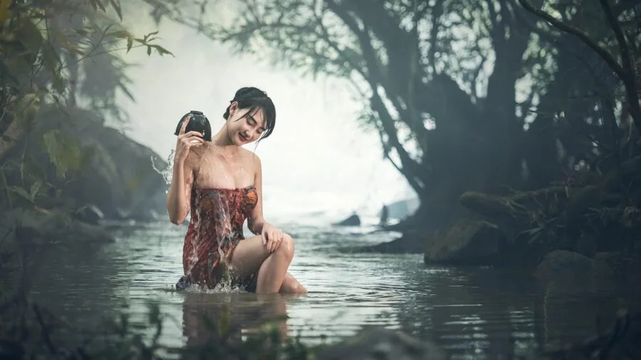 Woman rinsing hands under running water with water droplets splashing, demonstrating water resistance everyday use