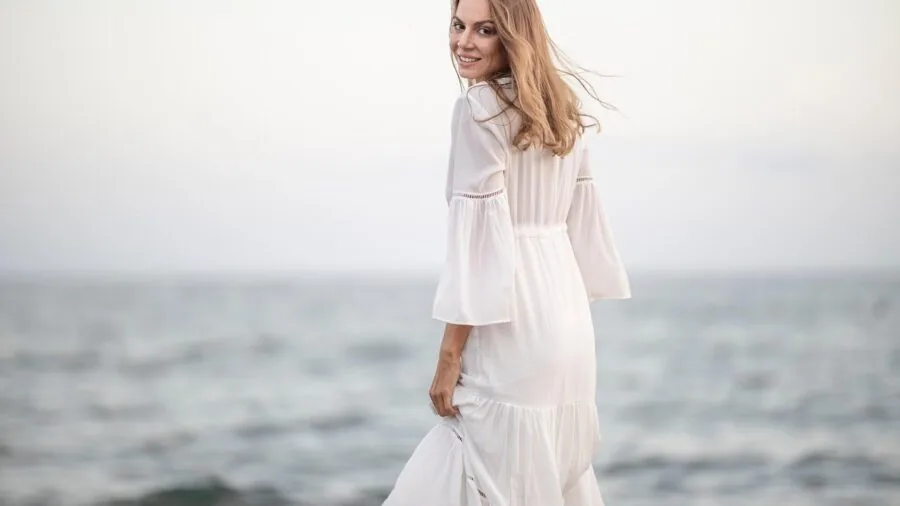 Woman selecting a vibrant colored dress from her wardrobe, representing modern wedding guest fashion choices