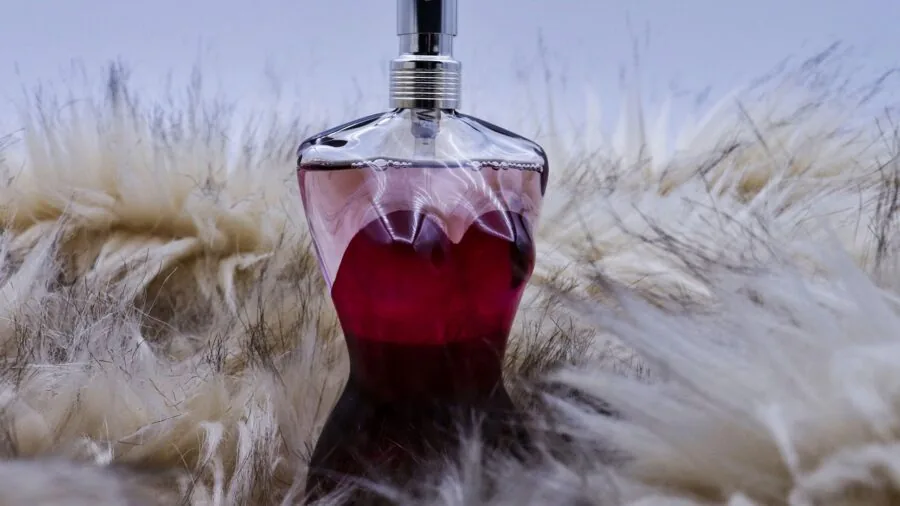 Woman selecting fragrance, smelling perfume bottle with contemplative expression in natural lighting