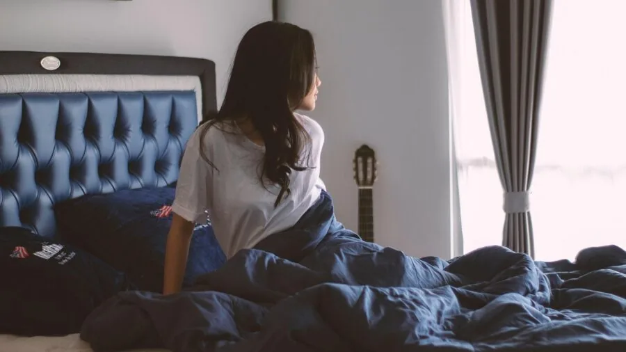 Woman sleeping peacefully on her side in bed with comfortable bedding and pillows