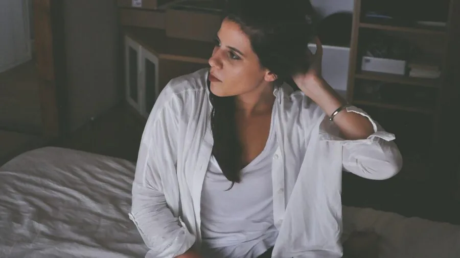 Woman smoothing and fitting a pillowcase onto a pillow on an unmade bed