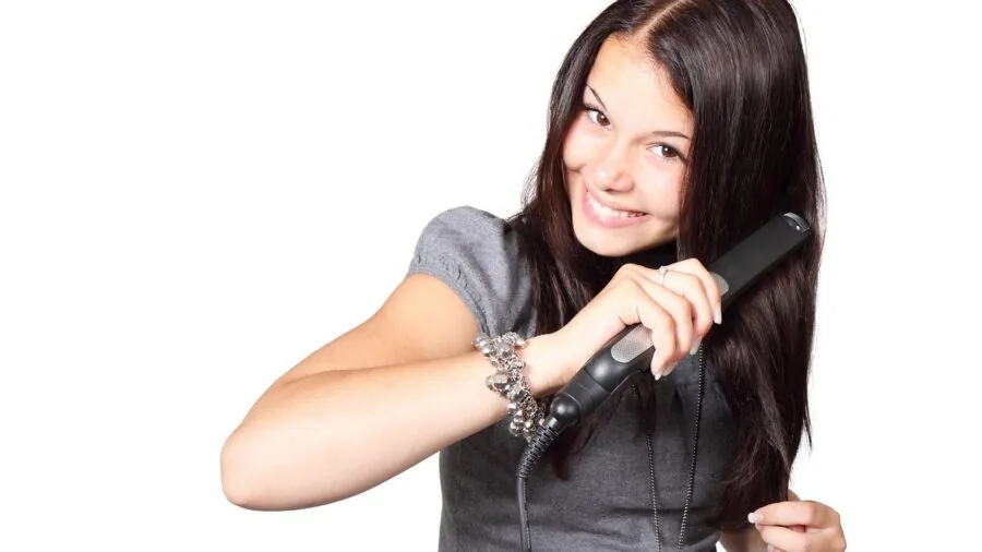 Woman smoothing hair with flat iron, demonstrating even glide through different hair textures