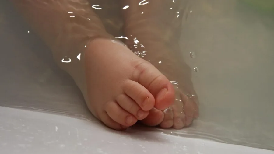 Woman soaking feet in warm water with natural spa ingredients during self-care wellness routine