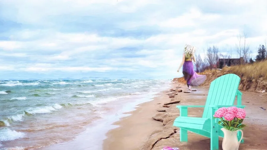 Woman strolling barefoot on sandy beach carrying flip-flops in hand during daytime
