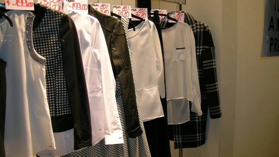 Woman thoughtfully examining clothing options while shopping, considering value and quality
