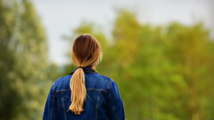 Woman tying her hair into a ponytail with elastic band for everyday styling