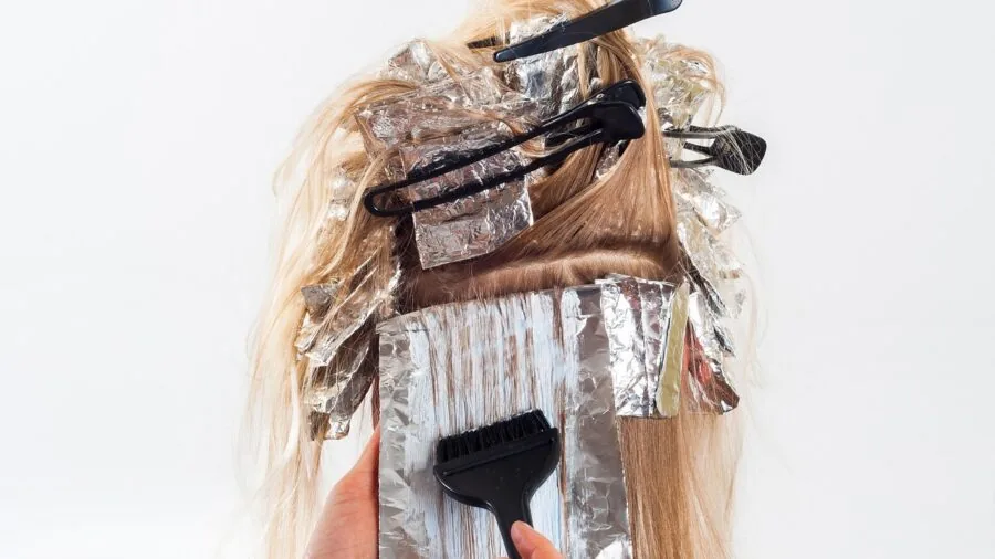 Woman using a hot-air styling brush to dry and style her hair at home