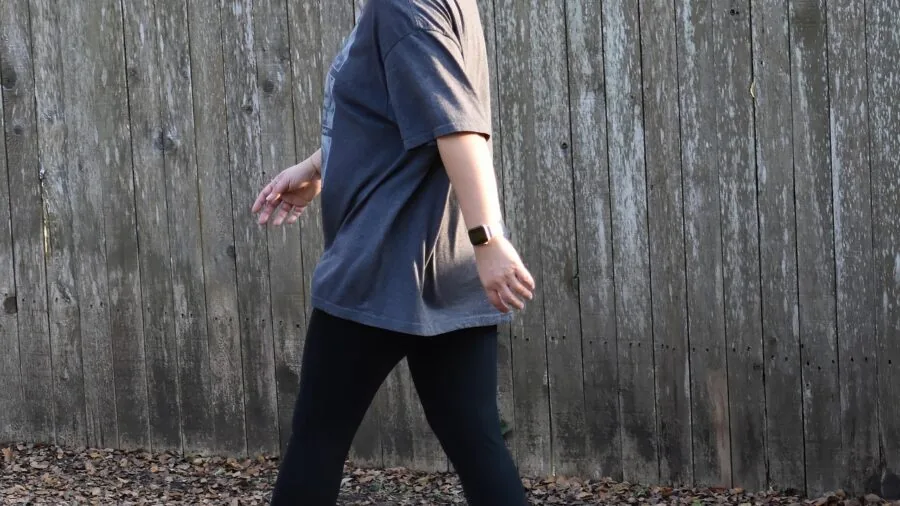 Woman walking outdoors during daytime exercise routine in natural setting