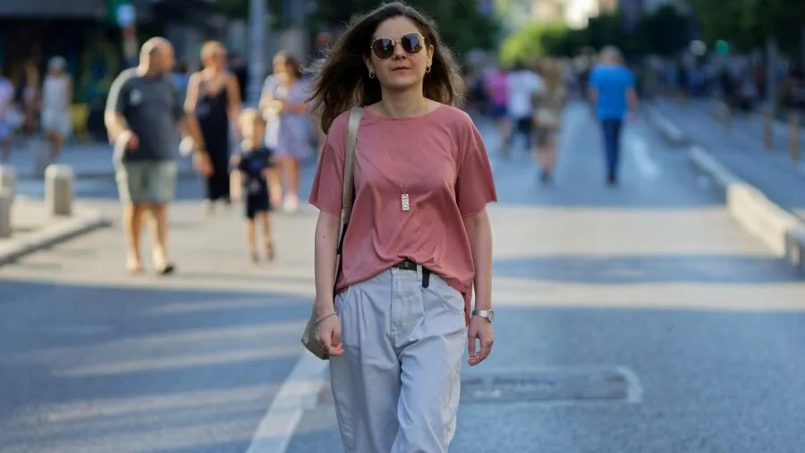 Woman wearing a crossbody bag while walking outdoors in everyday clothing
