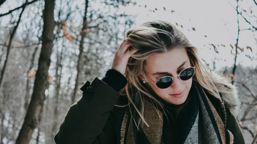Woman wearing cozy winter earmuffs and warm clothing outdoors in snowy landscape