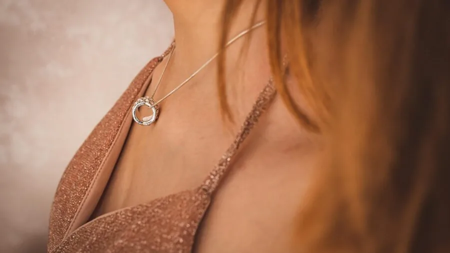 Woman wearing multiple layered necklaces with varied chain textures and styles in natural lighting