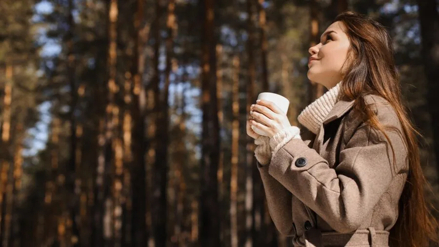Woman wearing winter coat checking pockets while outdoors in snowy setting
