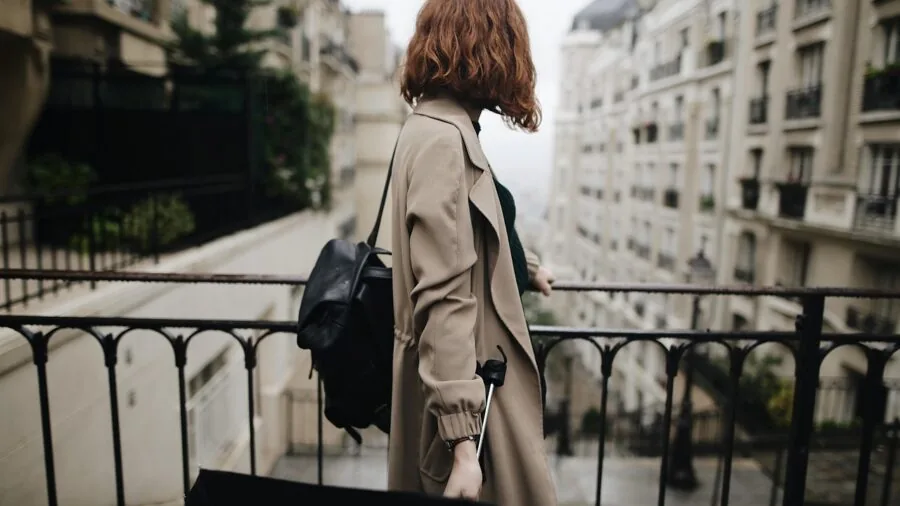 Woman with backpack walking through city street, casual everyday style