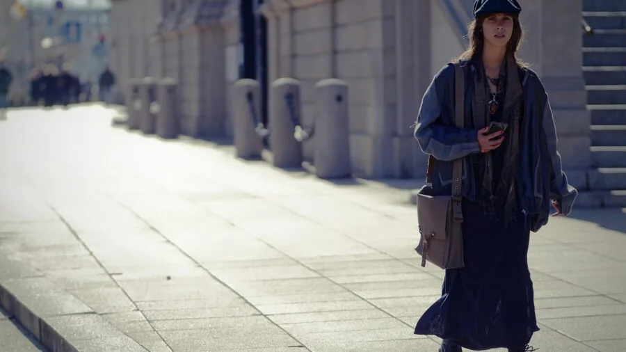 Woman with shoulder bag navigating through crowded urban street during travel