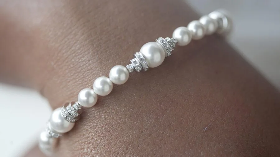 Woman's wrist displaying layered delicate bracelets in natural daylight, showing everyday jewelry styling