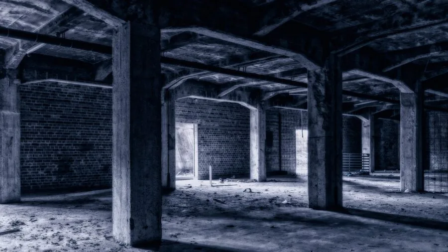 Worker in dim basement using handheld measurement tool with backlit display for construction task