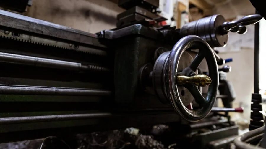 Worker in dusty industrial workshop with metal shavings and equipment