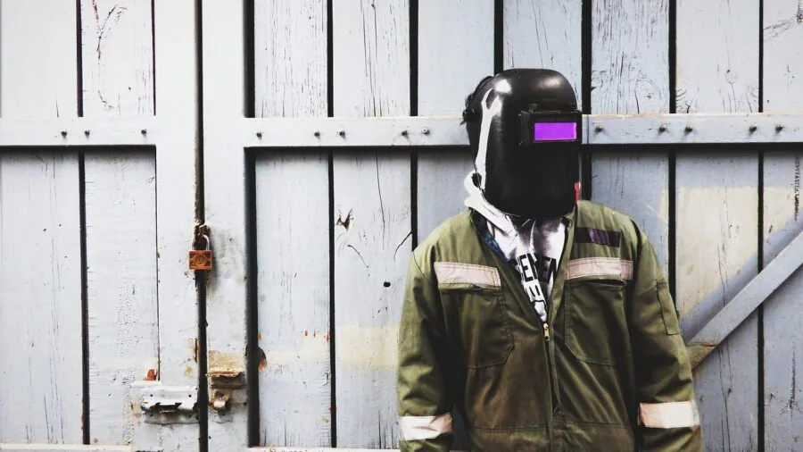 Worker in safety headphones at industrial workbench, focused on hearing protection during machinery operation