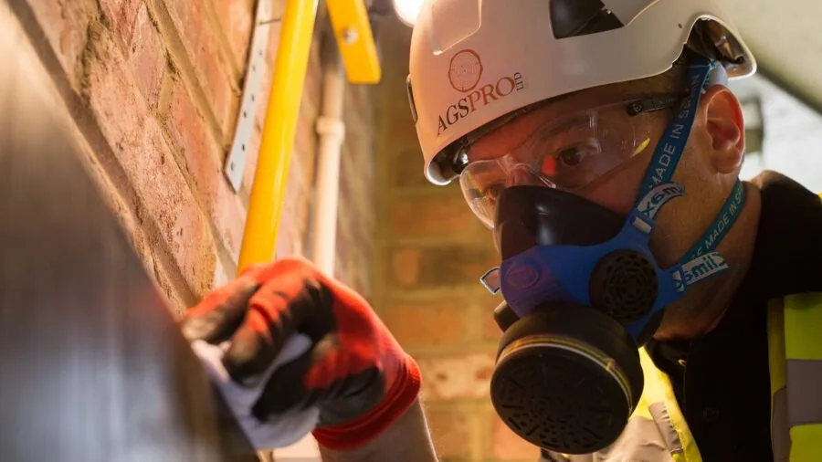 Worker inspecting protective gloves for safety standards compliance in industrial workplace