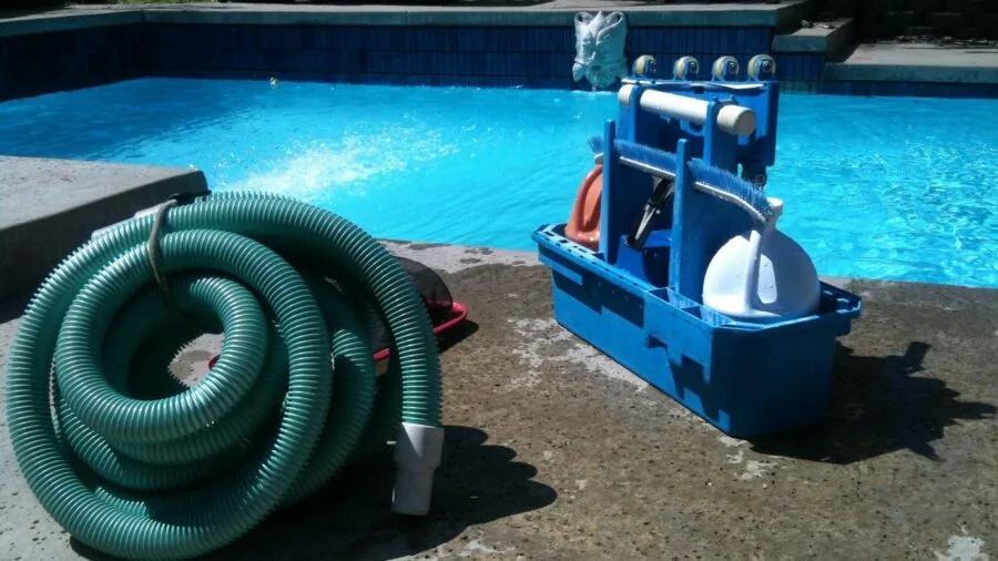 Worker maneuvering a long vacuum hose across a workshop floor during cleaning