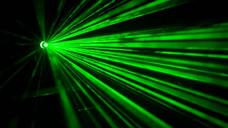 Worker using green laser level on interior wall construction project in bright daylight