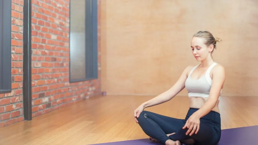 Yogi performing stretching exercise on cushioned mat indoors